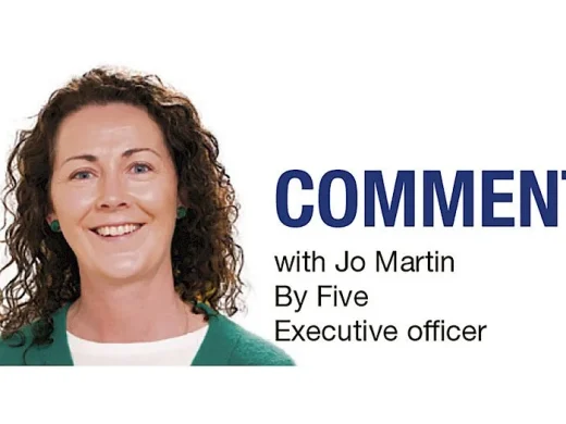 A woman with curly brown hair and a green jumper smiles at the camera. Text next to her reads: COMMENT with Jo Martin By Five Executive officer.